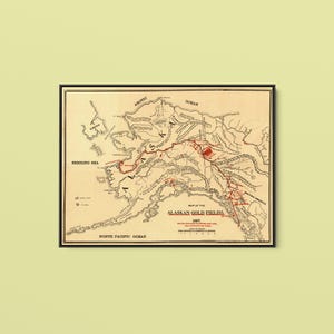 Puede incluir: Un mapa de estilo antiguo titulado Map of the Alaskan Gold Fields, 1897. El mapa presenta contornos en tinta negra sobre un fondo crema, con regiones específicas resaltadas en tinta roja. Muestra detalles geográficos de Alaska y áreas cercanas.
