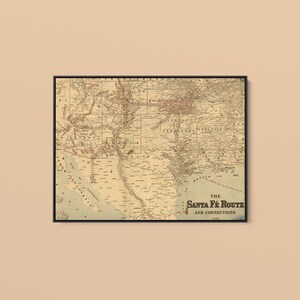 May include: A framed vintage map titled The Santa Fe Route and Connections, featuring detailed geographical lines, railway paths, and state boundaries in sepia tones. The print displays historical cartography of the American Southwest region.