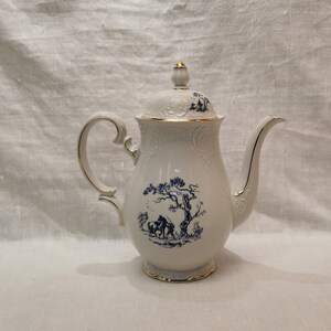 May include: White porcelain teapot with a blue and white floral design and gold trim. The teapot has a lid with a knob on top.