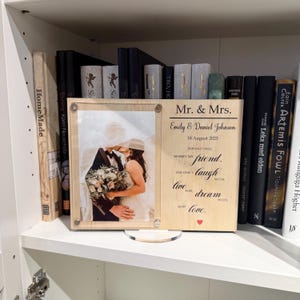 May include: A wooden wedding photo frame featuring a photograph of a kissing couple. The frame is inscribed with "Mr. & Mrs.", the names "Emily & Daniel Johnson", and the date "18 August 2025". A romantic quote about love is also included.