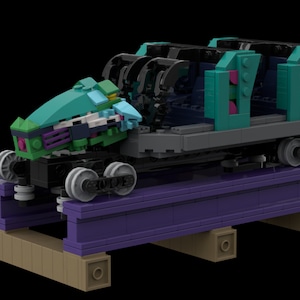 Puede incluir: Un modelo Lego de un vagón de montaña rusa en color turquesa, verde, morado y negro sobre una vía morada. El vagón tiene un letrero que dice "Iron Gwazi" y "671 pcs/Stck/pz/pzs/db".