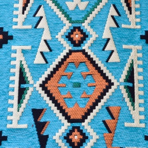 May include: A close-up of a blue and orange patterned fabric with a geometric design. The fabric has a woven texture and is made of a soft material.