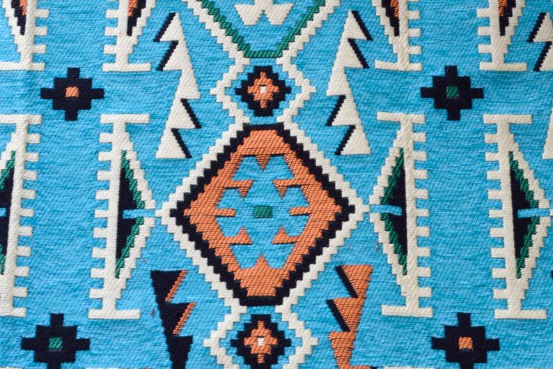 May include: A close-up of a blue and orange patterned fabric with a geometric design. The fabric has a woven texture and is made of a soft material.