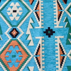 May include: A close-up of a blue, green, orange, and white patterned fabric with a geometric design.