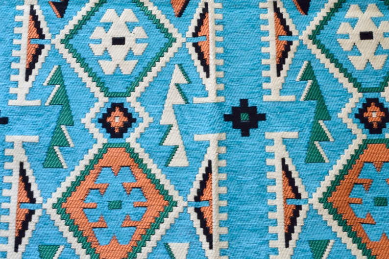 May include: A close-up of a blue, green, orange, and white patterned fabric with a geometric design.