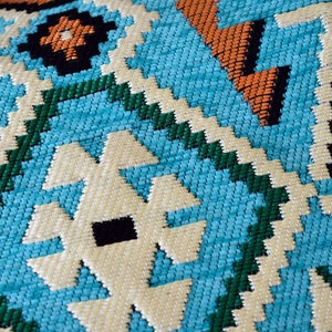 May include: Close-up of a blue, green, white, and orange woven fabric with a geometric pattern.