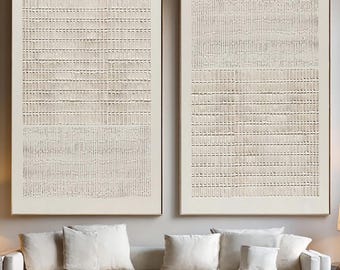 以下が含まれることがあります： ベージュとクリーム色の織り目模様の2つの大きな長方形の抽象芸術作品が白いソファの上に飾られています。アートワークは濃い色の木材で額装されています。部屋はニュートラルな色調で装飾されています。