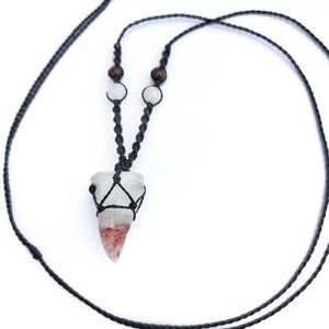 Puede incluir: Un collar hecho a mano con un colgante de cristal transparente con tonos rojos y blancos, sujeto en un tejido de macram&eacute; negro. El collar incluye un cord&oacute;n negro y peque&ntilde;as cuentas de madera y blancas. El colgante mide aproximadamente 3,8 cm de largo.