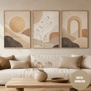 Op de afbeelding: Drie ingelijste abstracte kunstprints met een neutraal kleurenpalet van beige, bruin en zwart. De prints tonen een zon, een plant en een boog. Het kunstwerk wordt tentoongesteld boven een witte bank met beige kussens en een houten salontafel. De tekst "DIGITAL DOWNLOAD" is zichtbaar.