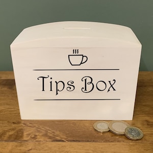 Op de afbeelding: Witte houten fooienbox met een zwart koffiekopje-icoon en de tekst "Tips Box".