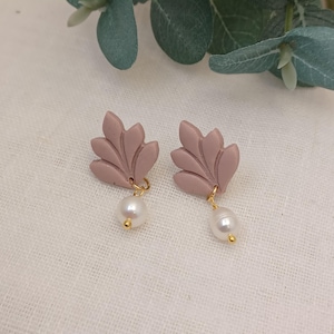 Puede incluir: Un par de pendientes de color rosa en forma de hoja con una perla que cuelga de cada uno. Los pendientes están hechos de arcilla polimérica y tienen un acabado dorado.