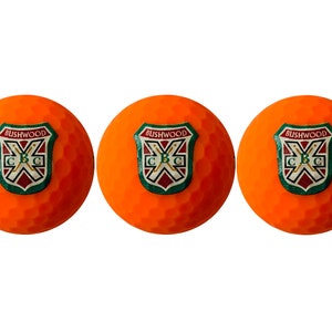 May include: Three orange golf balls with a green, red, and white logo that says "Bushwood C.B.C."