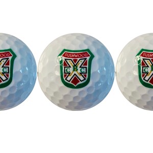 May include: Three white golf balls with a green, red, and white logo that says "Bushwood C.B.C."