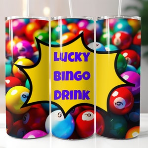 May include: A yellow and black comic book style speech bubble with the text "LUCKY BINGO DRINK" in purple letters. The background is a close-up of a pile of colorful bingo balls.