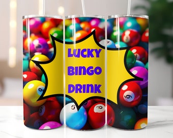 May include: A yellow and black comic book style speech bubble with the text "LUCKY BINGO DRINK" in purple letters. The background is a close-up of a pile of colourful bingo balls.