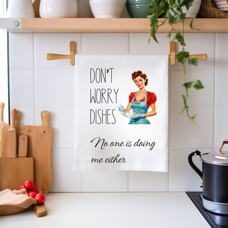 May include: White kitchen towel with a retro illustration of a woman washing dishes. The text reads "Don't worry dishes, No one is doing me either."