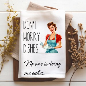 May include: White kitchen towel with a retro illustration of a woman holding a plate of dishes. The text reads "Don't worry dishes, No one is doing me either."