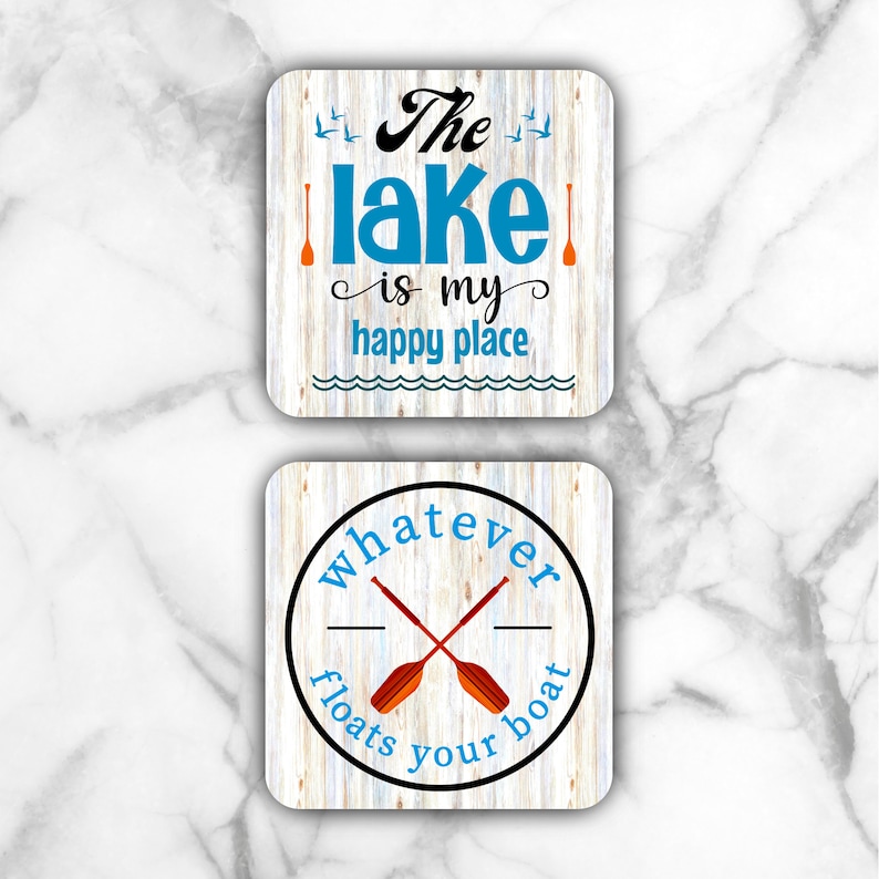 May include: Two square coasters with a wood grain background. The top coaster has the text "The lake is my happy place" in blue and black text with two orange oars. The bottom coaster has a black circle with the text "whatever floats your boat" in blue text and two orange oars crossed inside the circle.