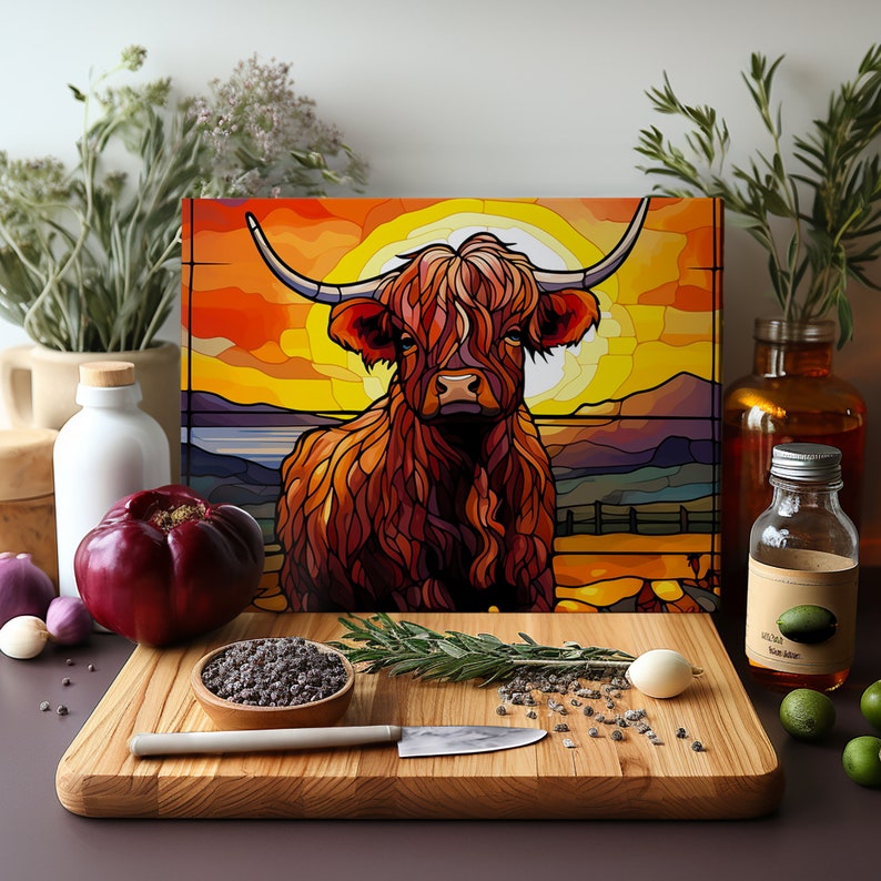 May include: A stained glass style illustration of a Highland cow standing in a field at sunset. The cow is brown and has long, shaggy hair. The background is a colorful sunset with a bright orange sun.