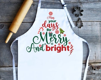 Könnte beinhalten: Weiße Küchenschürze mit einem Weihnachtsbaum-Design und dem Text "Mögen deine Tage fröhlich und hell sein".