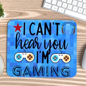 May include: Blue gaming mouse pad with a pixelated design. It features a red star, a pair of headphones, two game controllers, and the text "I CAN'T hear you I'M GAMING".
