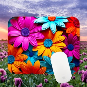 Puede incluir: Una alfombrilla de ratón colorida con un primer plano de flores de color rosa brillante, naranja, azul y rojo. La alfombrilla de ratón está sobre un campo de flores moradas.