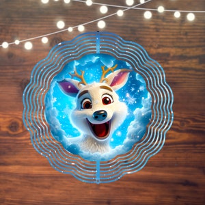 May include: A cheerful cartoon reindeer with golden antlers and a wide smile, set against a snowy blue background. The reindeer is framed by a decorative blue, wavy-edged circle. The background is a wooden surface with string lights.