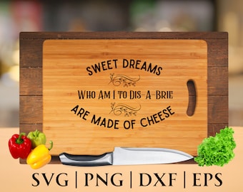 May include: A wooden cutting board with the text "SWEET DREAMS WHO AM I TO DIS-A-BRIE ARE MADE OF CHEESE" engraved on it. The board has a handle on the side.