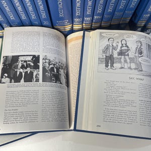 Może przedstawiać: Otwarta książka z czarno-białymi ilustracjami i tekstem. Jest częścią kolekcji niebieskich książek w twardej oprawie zatytułowanych "Knowledge". Strony zawierają obrazy i tekst.