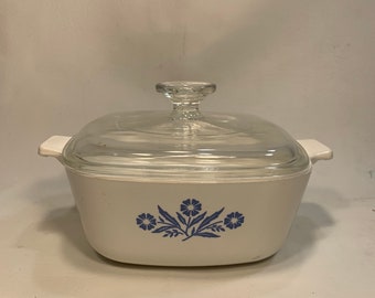 May include: White casserole dish with a blue floral design and a clear glass lid.
