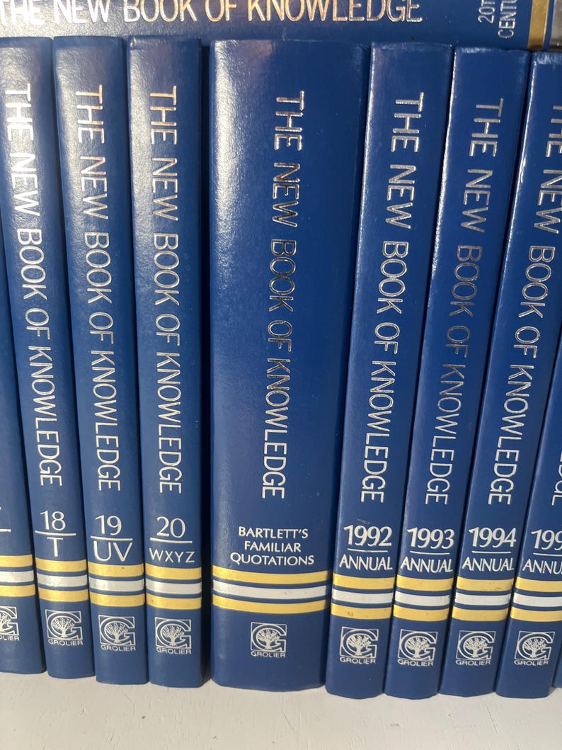 Może przedstawiać: Kolekcja niebieskich książek w twardej oprawie zatytułowanych "The New Book of Knowledge". Grzbiety mają złote litery i zawierają numery tom&oacute;w oraz tytuł "Bartlett's Familiar Quotations". Książki pochodzą od Grolier.