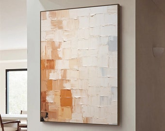 Puede incluir: Pintura abstracta con fondo blanco y cuadrados naranja y marrón. La pintura está colgada en una pared blanca en una habitación con una silla blanca y un taburete de madera.