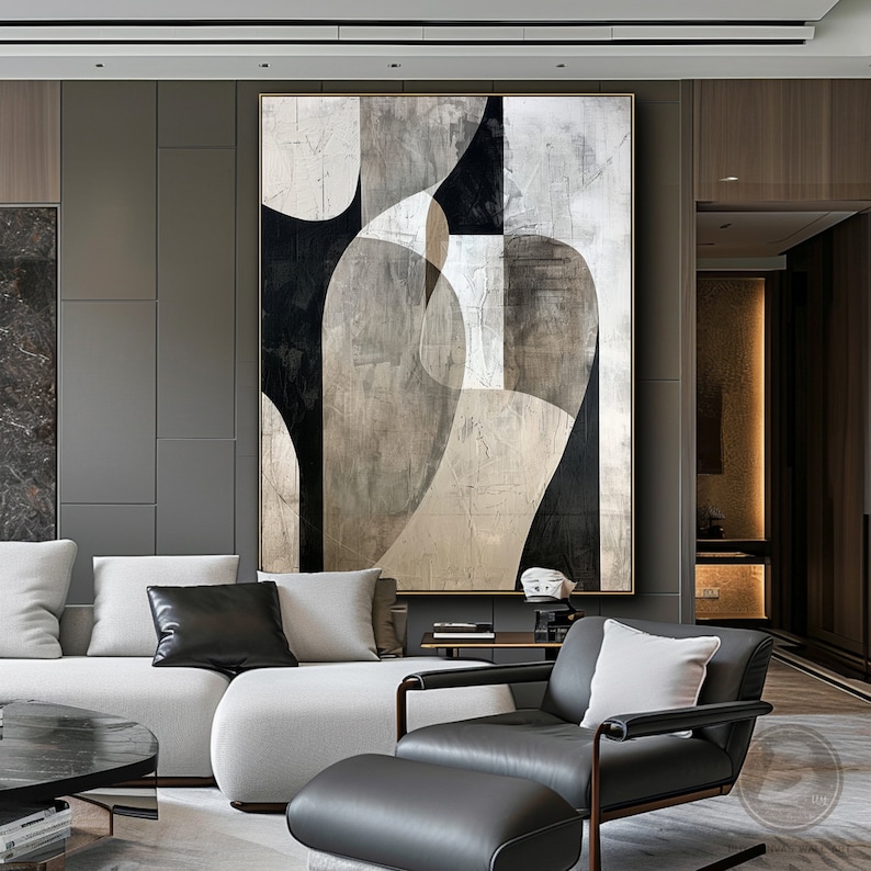 May include: Abstract art painting with black, white, and gray geometric shapes on a textured canvas. The painting is framed in a gold frame and hangs on a gray wall in a modern living room.