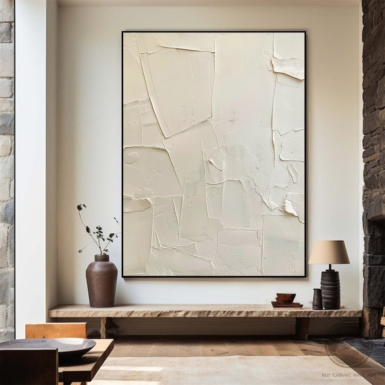May include: A large, abstract painting with a white background and textured brushstrokes. The painting is framed in black and is hanging on a white wall.