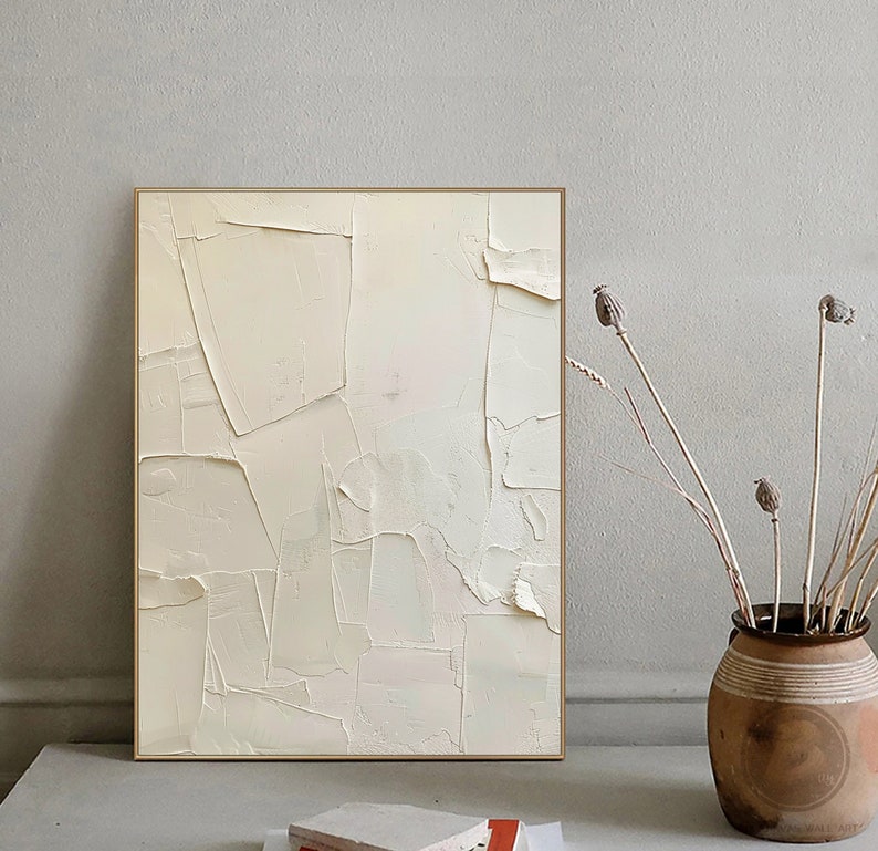May include: Abstract painting with a textured, off-white background. The painting is framed in a thin, gold frame.