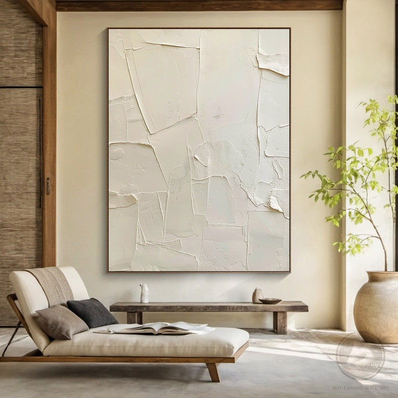 May include: A large, abstract painting with a white background and textured brushstrokes. The painting is framed in a thin, brown frame and is hanging on a wall in a modern living room.