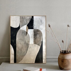 May include: Abstract art painting with geometric shapes in black, white, and gray tones. The painting is framed in a light wood frame and is hanging on a white wall.