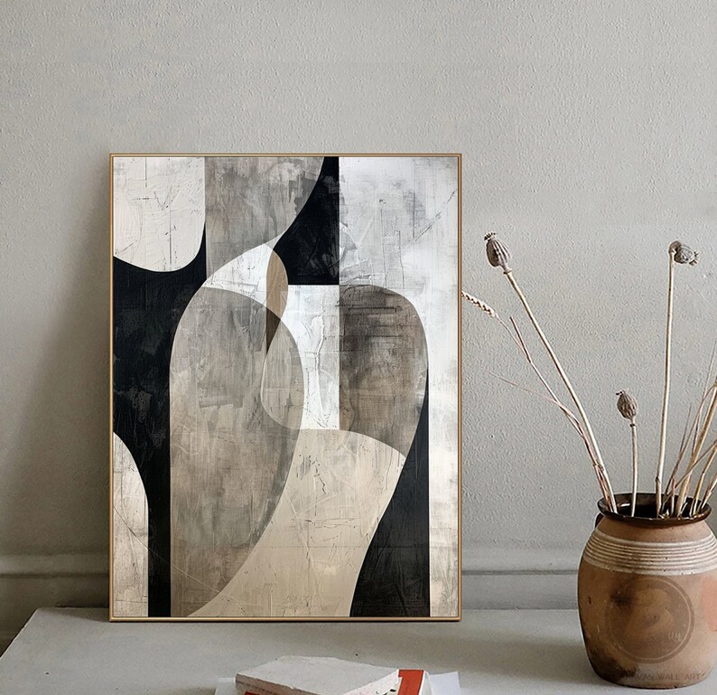 May include: Abstract art painting with geometric shapes in black, white, and gray tones. The painting is framed in a light wood frame and is hanging on a white wall.