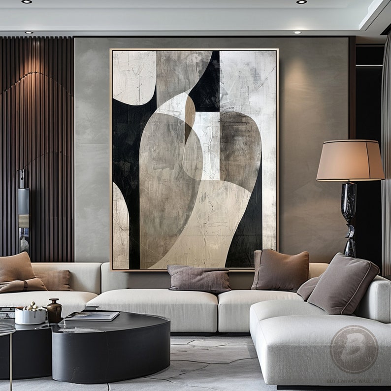 May include: Abstract art print with black, white, and gray geometric shapes on a textured canvas. The print is hanging on a wall in a modern living room with a white sectional sofa and a coffee table.