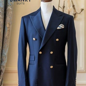 May include: A navy blue double-breasted suit with gold buttons is displayed on a mannequin. The suit features a notched lapel, a pocket square, and the text "SWANKY SUITS". The suit is tailored and appears to be made of a high-quality fabric.