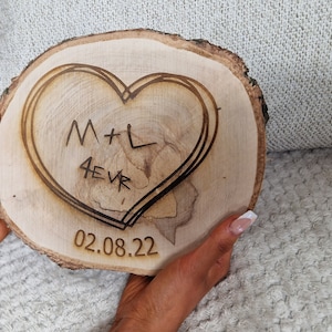 May include: A wooden heart-shaped plaque with the initials "M+L" and the text "4EVR" burned into the wood. The date "02.08.22" is also burned into the wood.