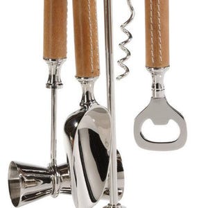 May include: A silver bar tool set with brown leather handles. The set includes a bottle opener, a corkscrew, a jigger, and a bar spoon. The tools are mounted on a silver stand.
