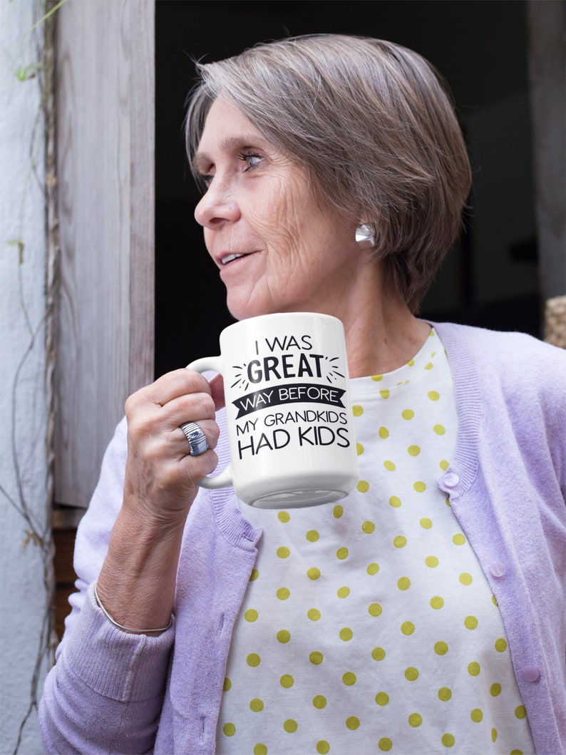 May include: White ceramic mug with black text that reads "I was great way before my grandkids had kids".