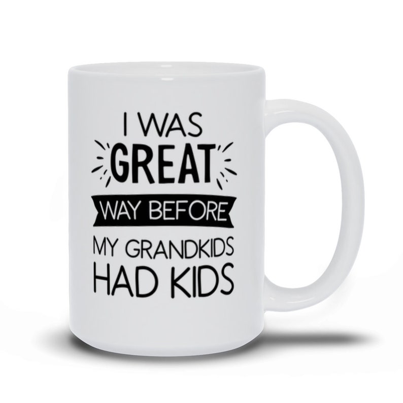 May include: White ceramic coffee mug with black text that reads "I was great way before my grandkids had kids".