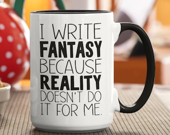 Może przedstawiać: Biały ceramiczny kubek z czarnym wnętrzem i uchwytem. Z przodu znajduje się czarny napis: I WRITE FANTASY BECAUSE REALITY DOESN'T DO IT FOR ME. Kubek ma cylindryczny kształt z solidnym uchwytem po prawej stronie.