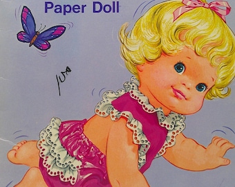 May include: Vintage "Baby Thataway" paper doll book cover. The illustration features a crawling baby doll with blonde curly hair, wearing a pink outfit with white lace trim. A butterfly and the text "Baby Thataway Paper Doll" are also visible.