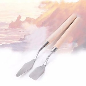 May include: Two stainless steel palette knives with wooden handles. The knives have a curved blade and are used for mixing and applying paint.