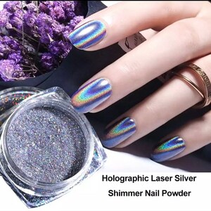 May include: A jar of holographic laser silver shimmer nail powder. The powder is a fine, glittery texture and is shown on a hand with nails painted with the powder.