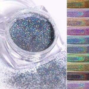 May include: A clear jar filled with iridescent glitter. The glitter is a mix of silver, blue, green, and purple. The jar is sitting on a white surface.