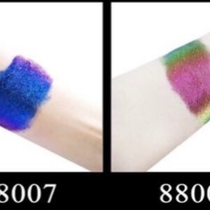 Op de afbeelding: Twee swatches van iriserende glitterverf op de huid. De swatch aan de linkerkant is diepblauw met een paarse glans. De swatch aan de rechterkant is een meerkleurige iriserende glitter met een roze basis. De swatches zijn ge&euml;tiketteerd met 88007 en 88008.